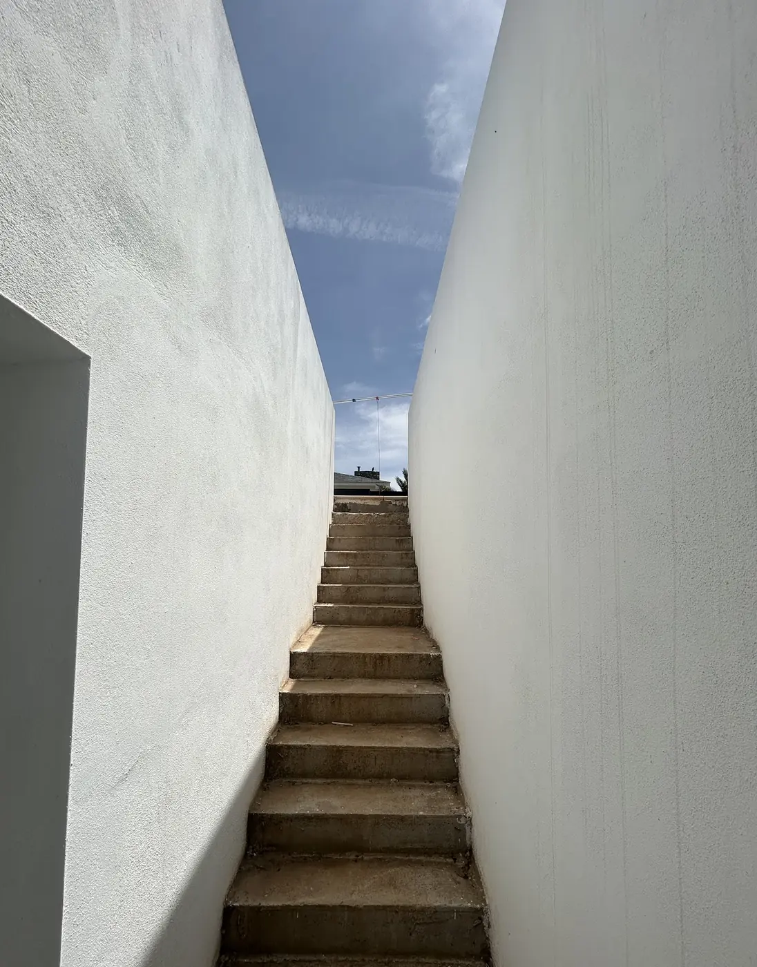 Escalera exterior entre dos muros blancos