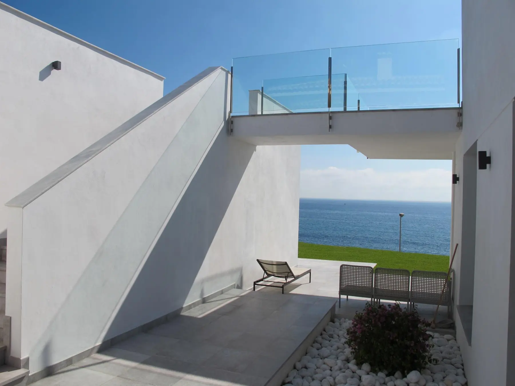 Pasaje bajo la terraza de una casa blanca que enmarca el mar