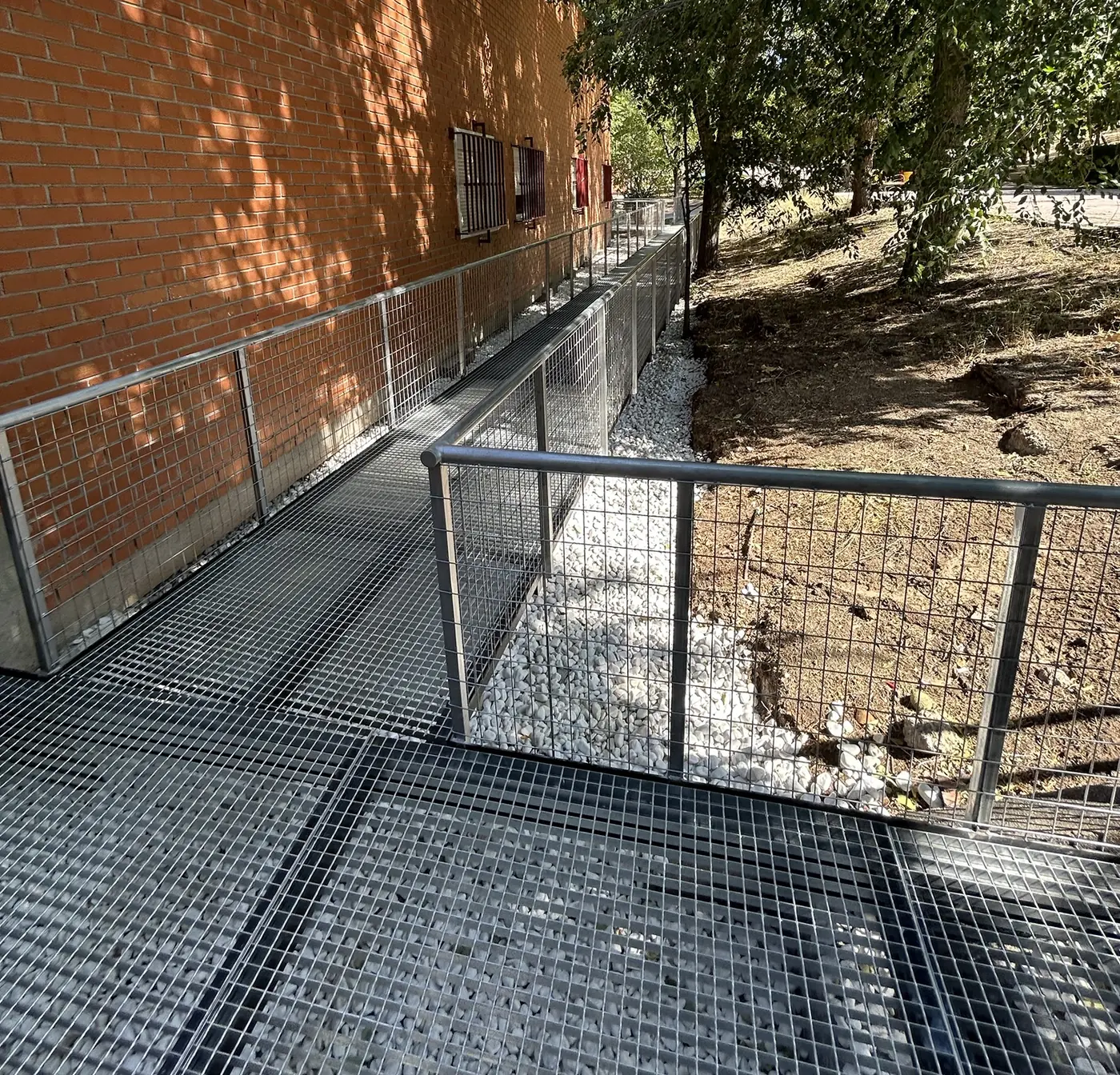 Tramo de rampa junto a la fachada y el talud ajardinado